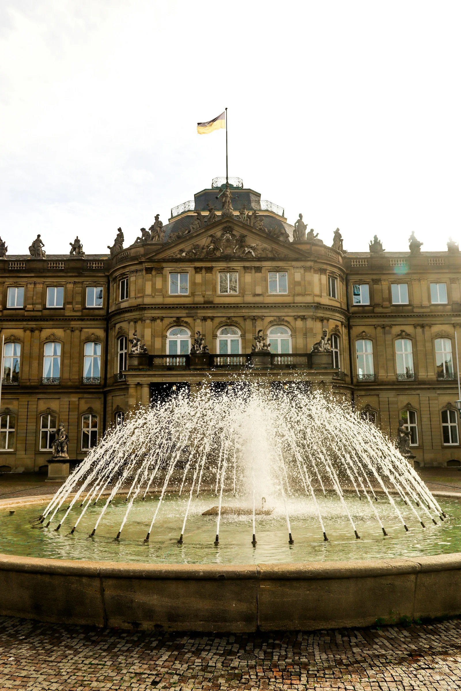 Decorative water jets in a circular stone fountain before a historic facade