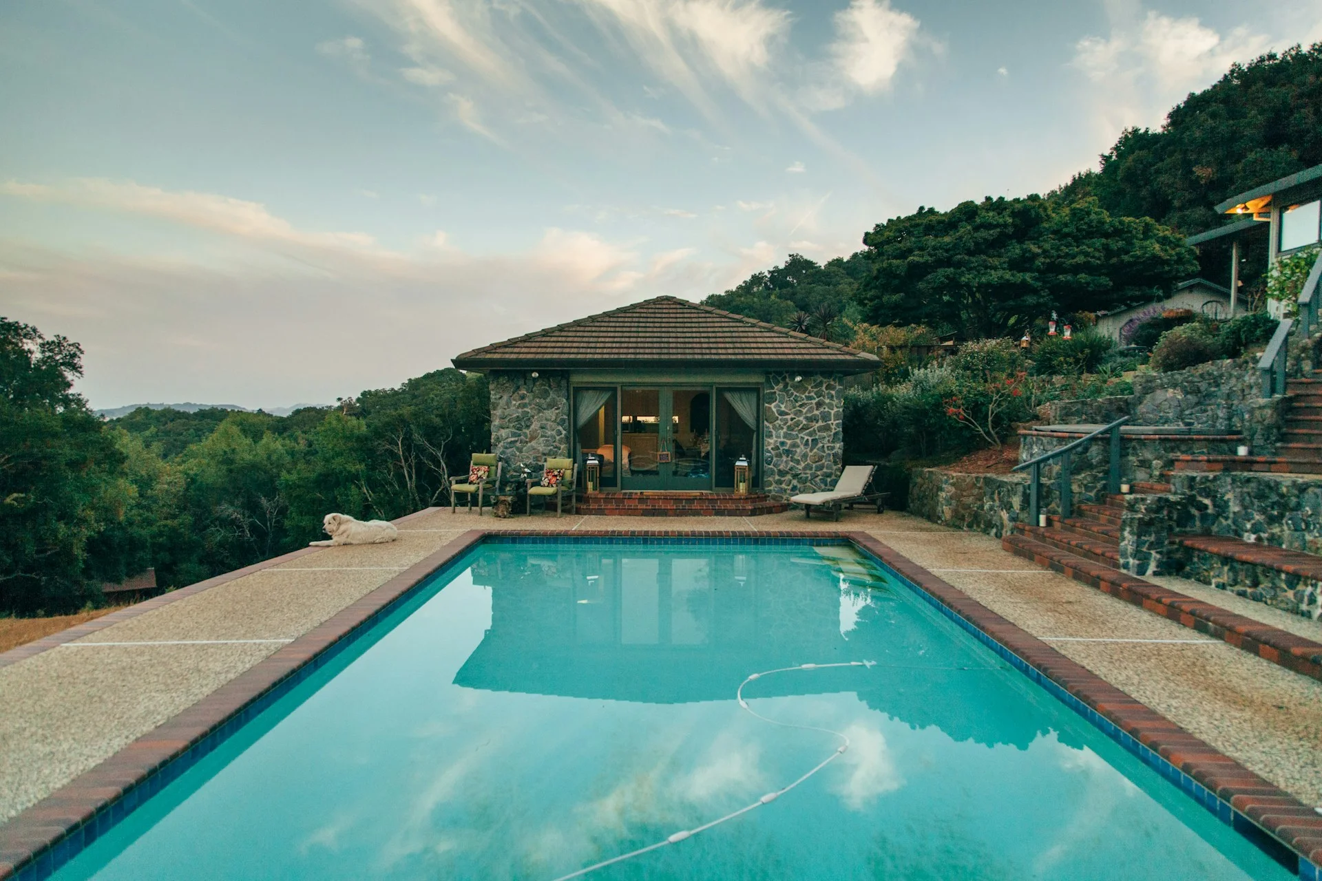Outdoor swimming pool with a tiled border and stone terrace